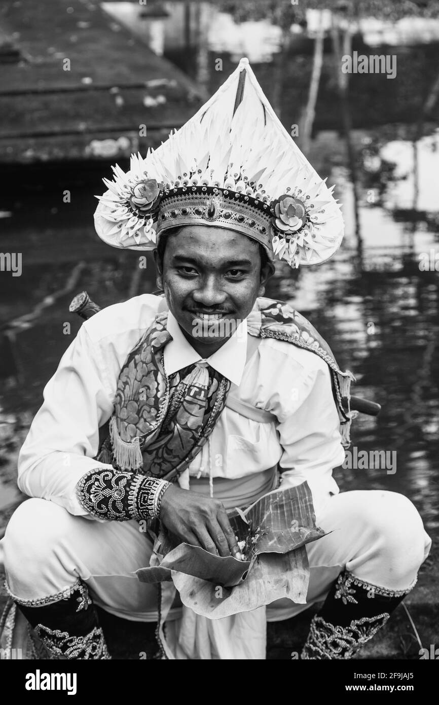 Ein junger Mann im Kostüm, der Mittagessen auf EINEM Hindu-Festival, dem Wassertempel von Tyrta Empul, Bali, Indonesien, isst. Stockfoto