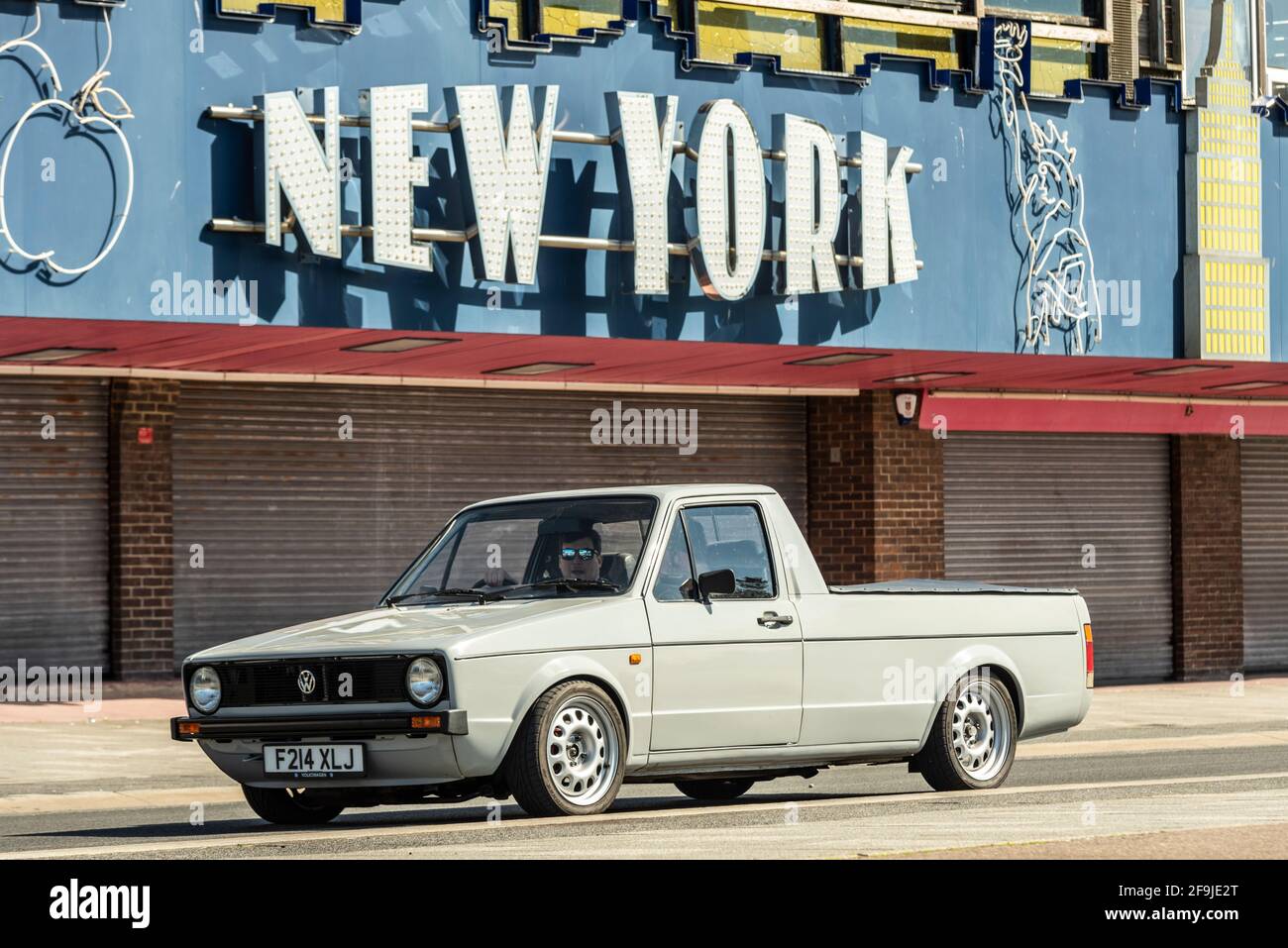 1989 Volkswagen Caddy Pickup-Truck fährt an einem sonnigen, hellen Frühlingstag an einer geschlossenen New Yorker Spielhalle in Southend on Sea, Essex, Großbritannien, vorbei. Stockfoto