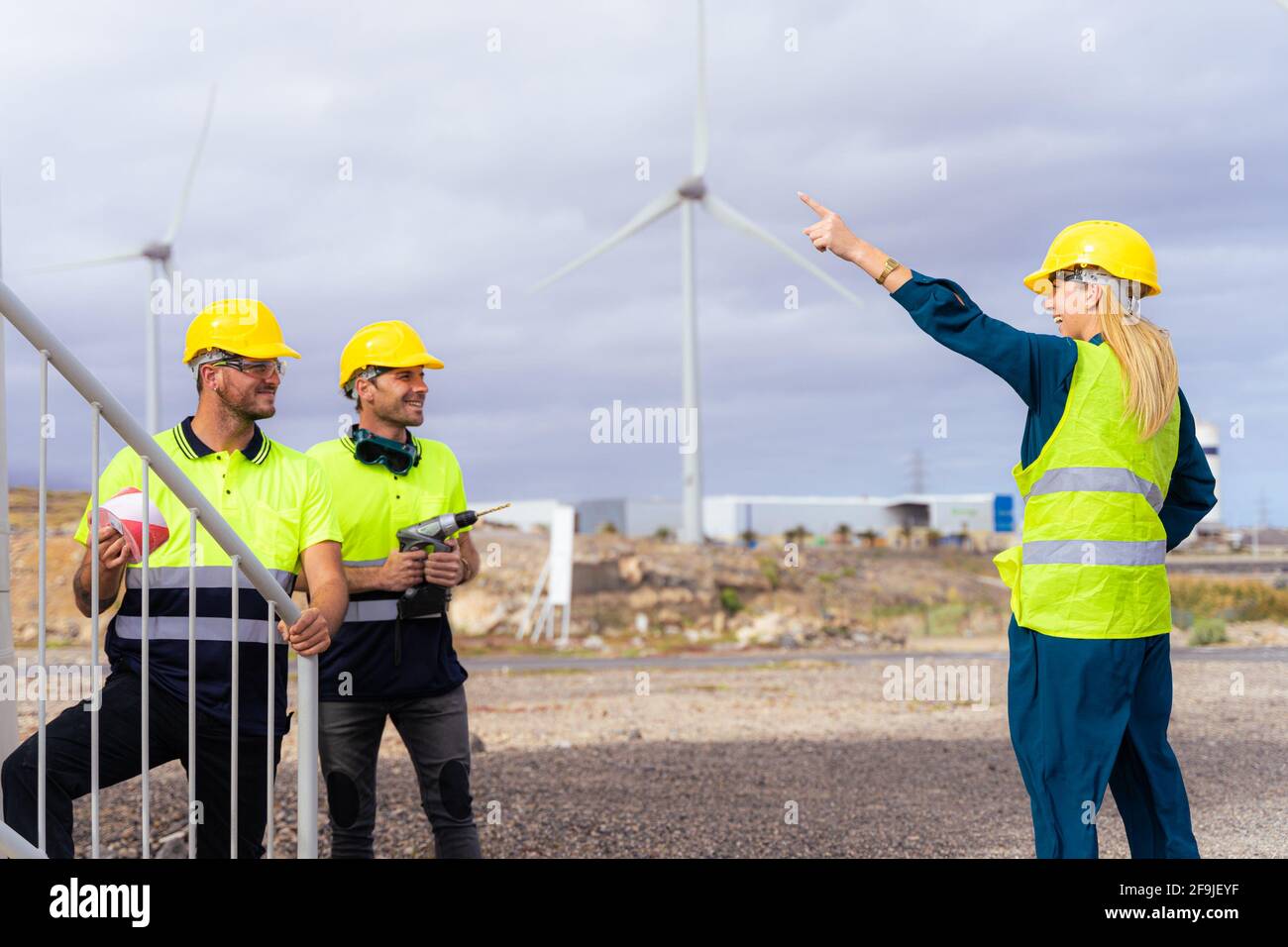 Zwei qualifizierte Arbeiter hören den Erklärungen der Ingenieurin Frau über die Nuancen der Arbeit zu. Erneuerbare Energien und professionelles Arbeitskonzept. Stockfoto