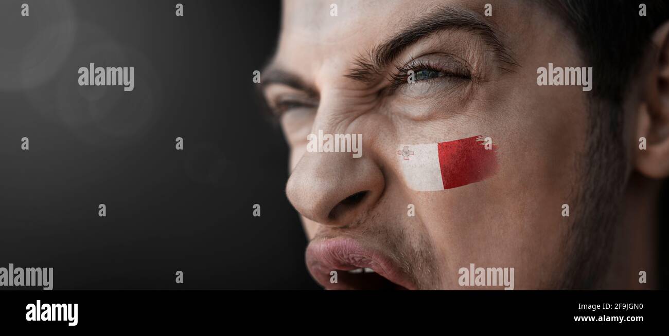 Ein schreiender Mann mit dem Bild des Maltas Flagge auf seinem Gesicht Stockfoto