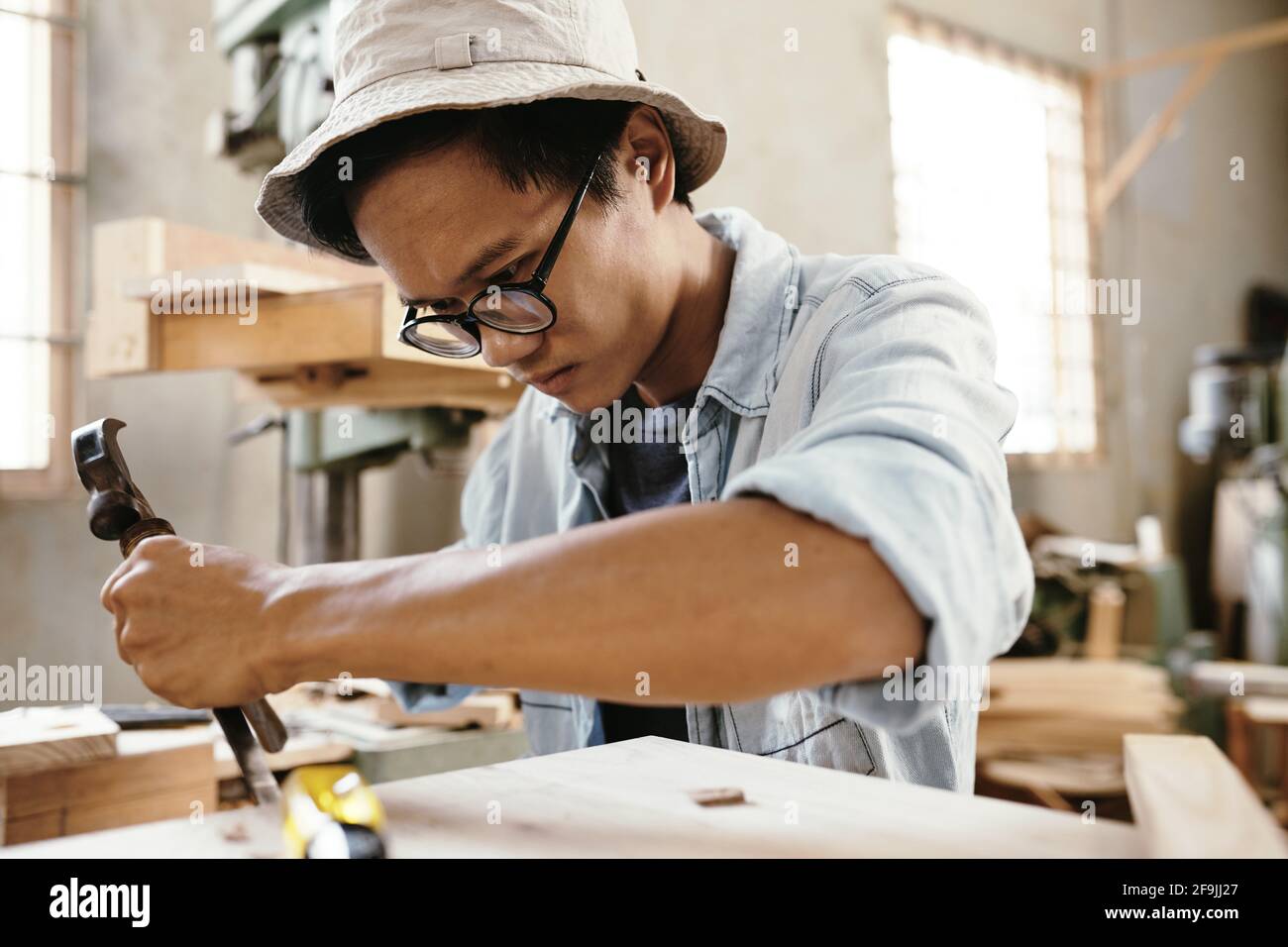 Der Zimmermann konzentrierte sich darauf, Brocken aus der Oberfläche des Holzes zu nehmen Bei der Herstellung von Möbelstücken Stockfoto