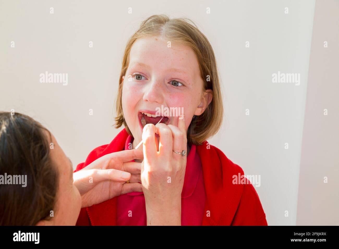 Kind im Schulalter Kind Grundschule Mädchen von 11 Jahre alt / Jahre alt, die Proben aus ihrem Hals für die Verwendung in einem lateralen Durchflusstest LFT von der chinesischen Firma Innova entnommen. England, Großbritannien. (123) Stockfoto