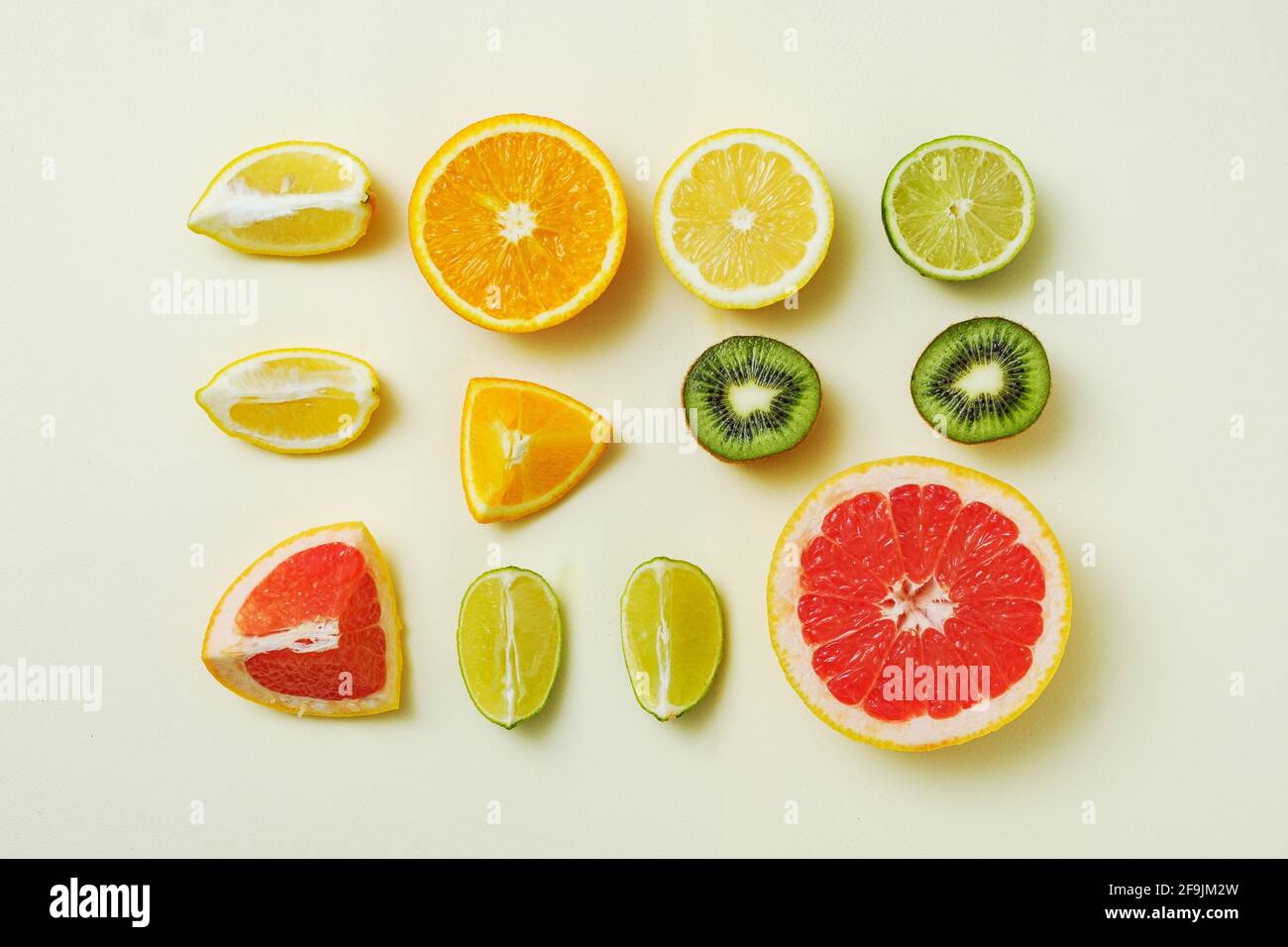 Gemischte Sommerfrüchte auf gelbem Hintergrund in geometrischer Reihenfolge - Zitrone, Orange, Limette und Grapefruit in Stücke geschnitten - Minimal trendy Konzept Stockfoto