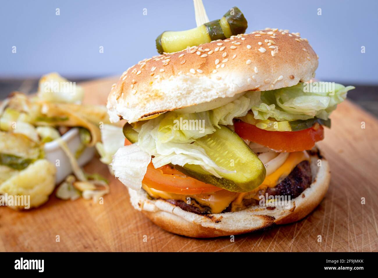 Köstlicher hausgemachter Käse-Burger mit Dill-Pickles aus der Nähe Holztisch Stockfoto