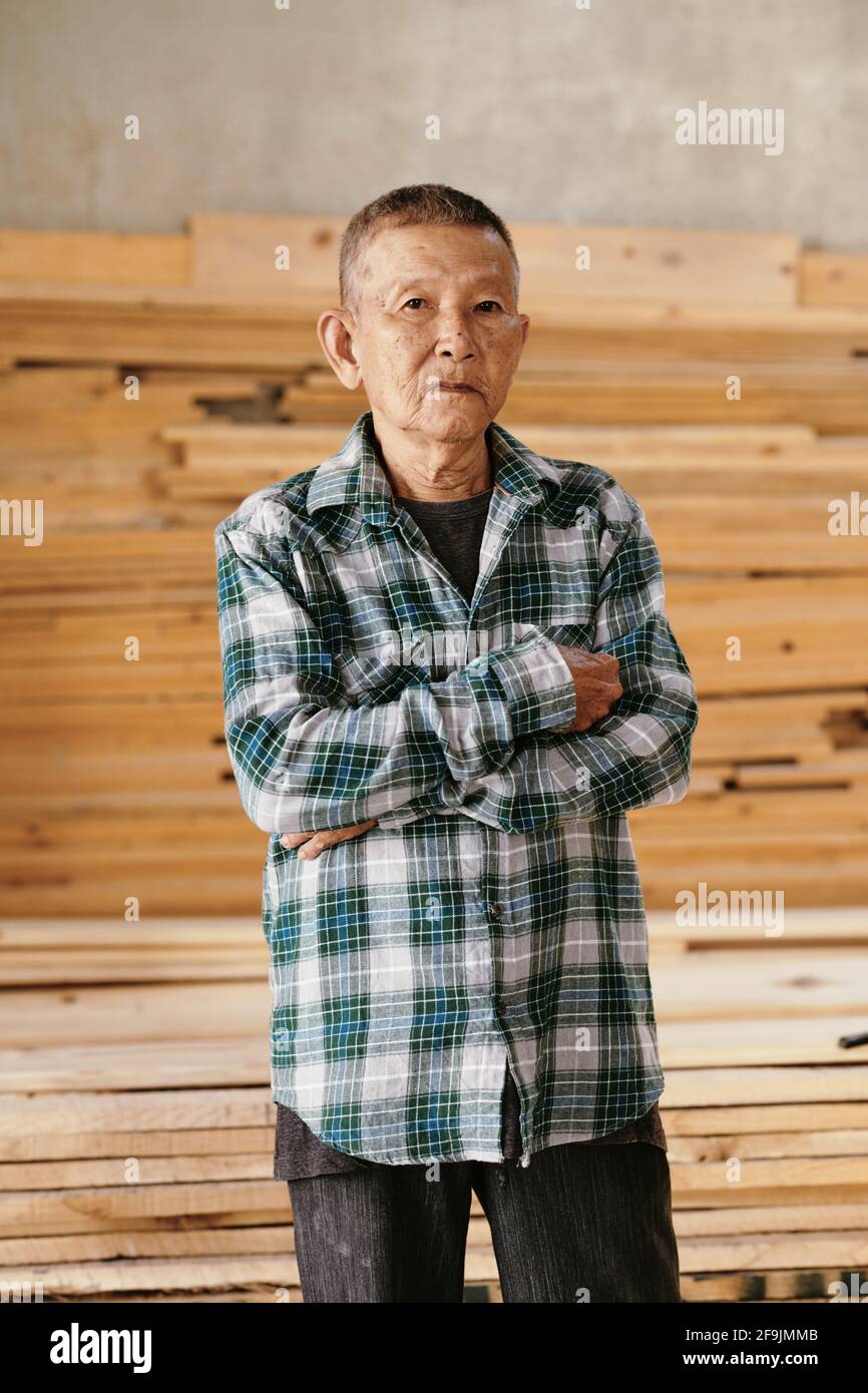 Porträt eines ernsthaften vietnamesischen Zimmermanns in karierten Hemdübergängen Arme und Blick auf die Kamera Stockfoto