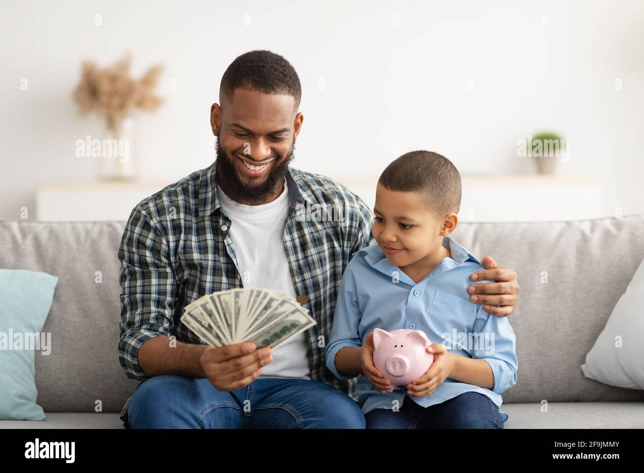 Papa Hält Geld Im Gespräch Mit Sohn Über Persönliche Ersparnisse Indoor Stockfoto