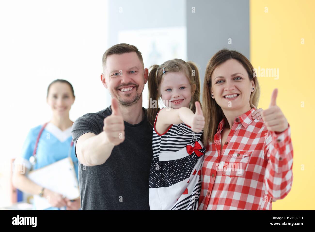 Eltern und kleines Mädchen zeigen beim Arzttermin Daumen nach oben Stockfoto