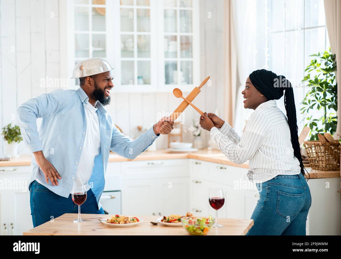 Lustige Schwarze Paar Mit Spaß In Der Küche, Mit Küchengeräten Für Spiel Kämpfen Stockfoto