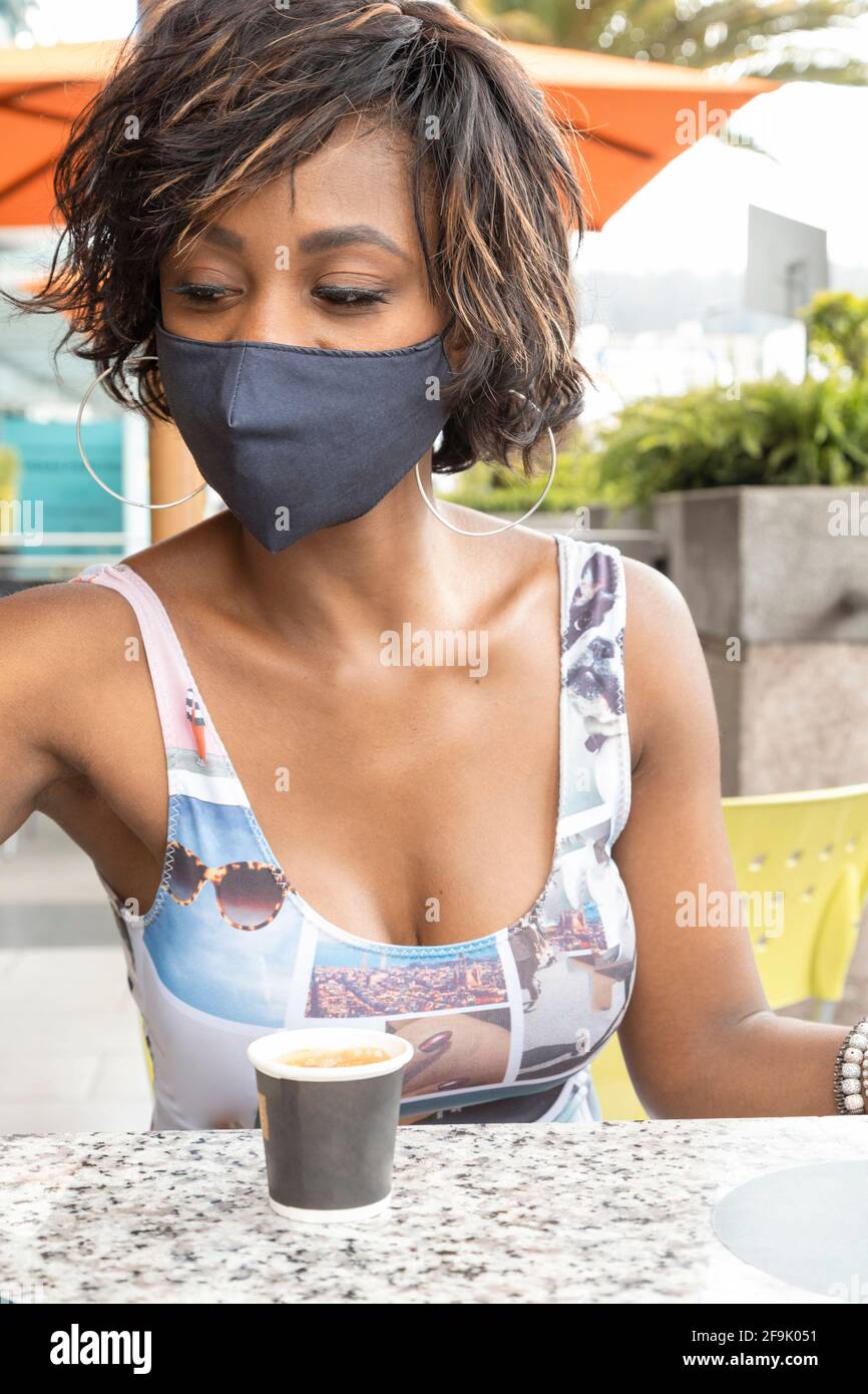 Nahaufnahme des Gesichts einer afroabhängigen Frau mit kurzen Haaren, im Freien in legerer Kleidung und geschützt mit Maske, Schönheit und Modernität Stockfoto