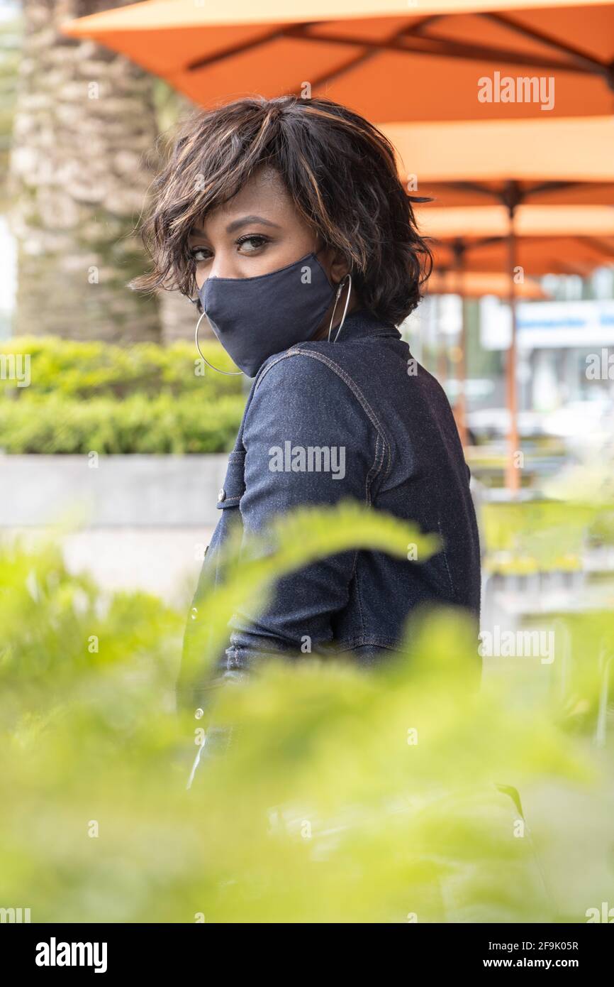 Outdoor-Café mit einer Frau mit kurzen Haaren und einem schönen Look trägt Make-up, eine Maske und jean-Jacke, Beauty-Modell in der Stadt Stockfoto