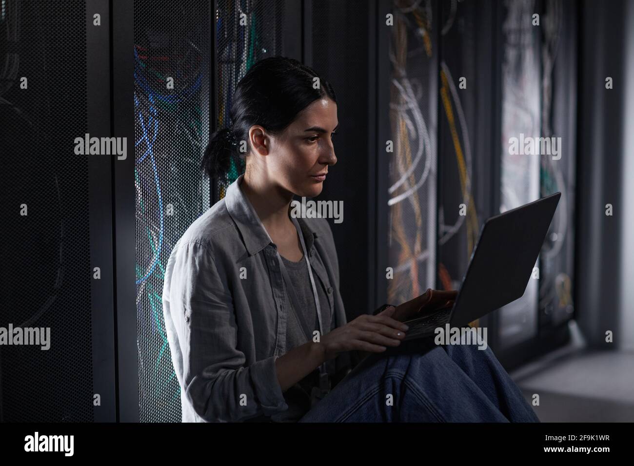 Seitenansicht Porträt einer weiblichen IT-Ingenieurin, die einen Laptop im Serverraum verwendet, während sie mit einem Supercomputer im Rechenzentrum arbeitet, Kopierplatz Stockfoto