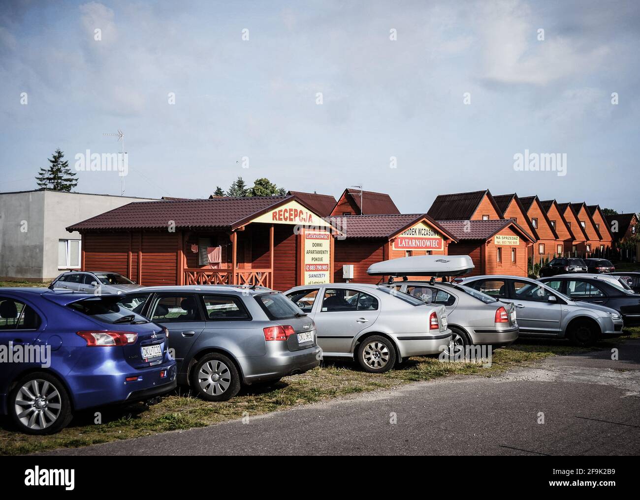 SIAN, POLEN - 27. Okt 2016: Reihe geparkter Autos vor hölzernen Ferienhäusern Stockfoto