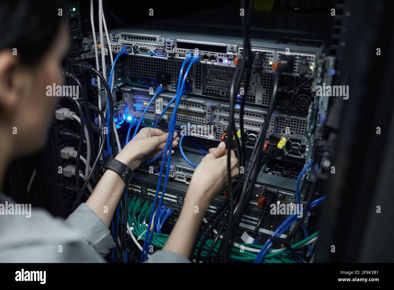 Nahaufnahme einer Netzwerktechnikerin, die Kabel im Serverschrank anschließt, während der Supercomputer im Rechenzentrum eingerichtet wird, Platz kopieren Stockfoto