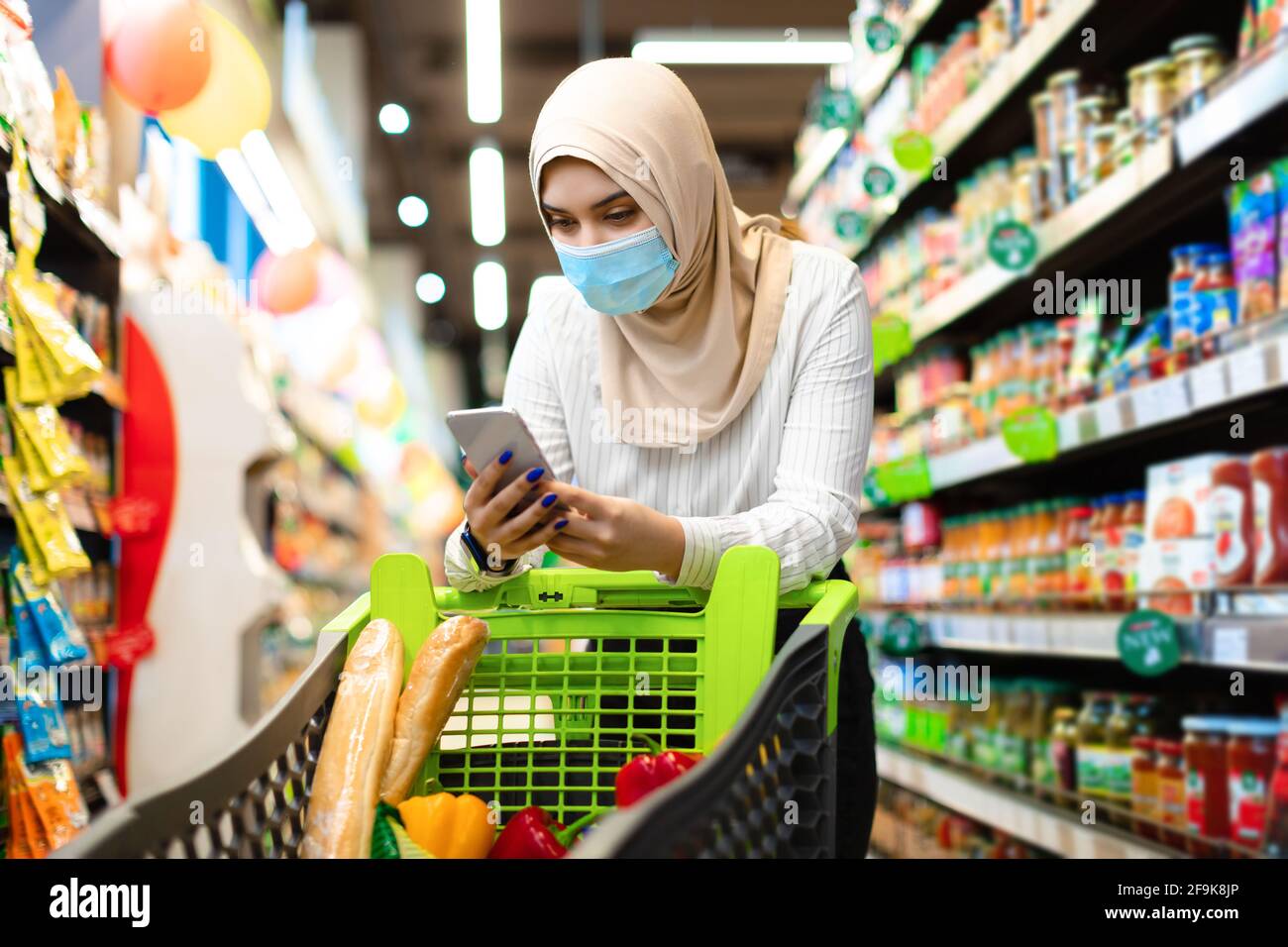 Islamische Frau Auf Lebensmittelgeschäft Einkaufen Im Supermarkt Mit Smartphone Stockfoto
