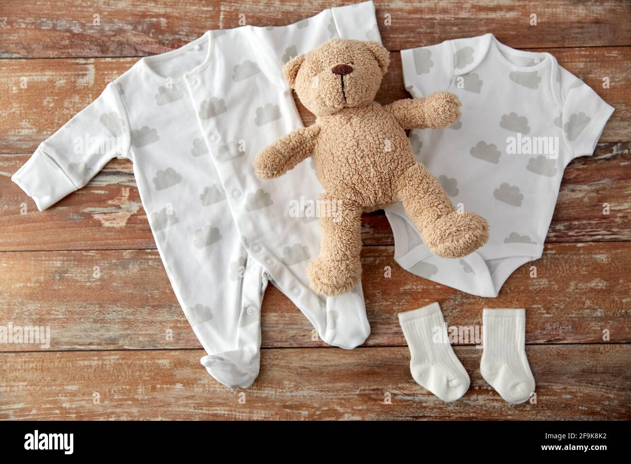 Babybody und Teddybär auf Holztisch Stockfoto
