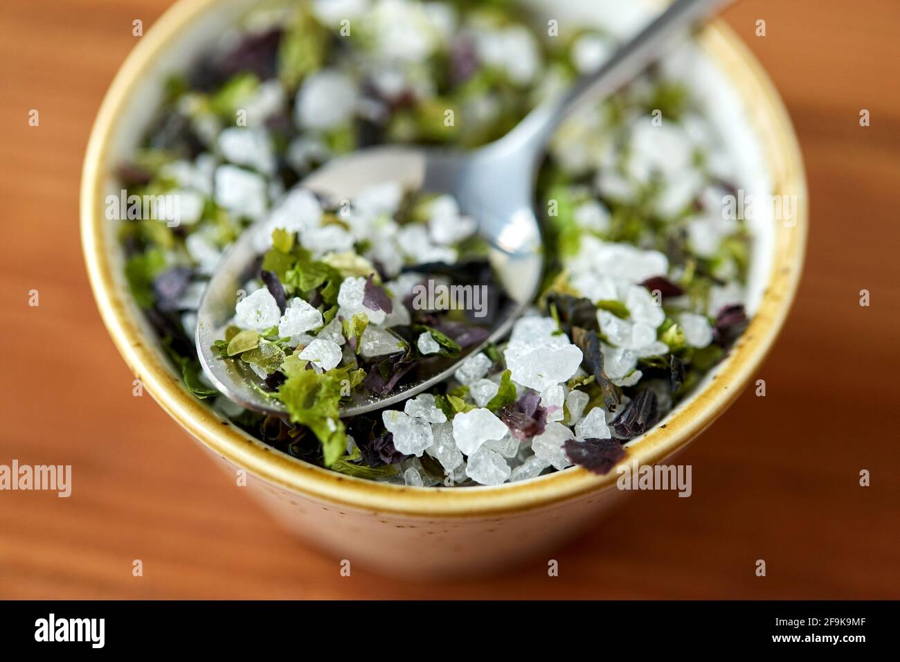 Nahaufnahme von aromatisiertem Meersalz in einer Schüssel mit Löffel Stockfoto