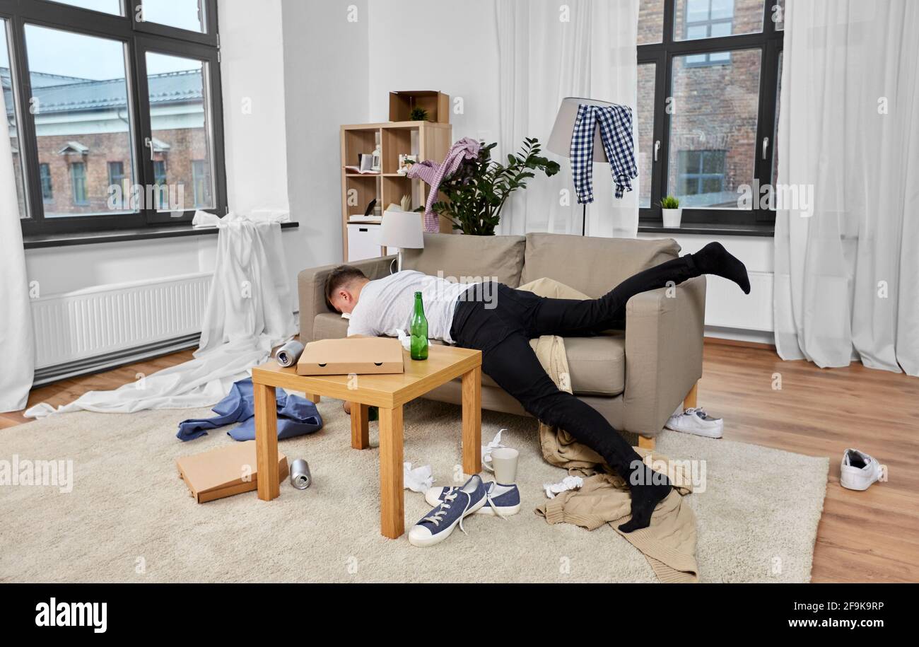 Betrunkener Mann, der zu Hause auf dem Sofa in einem schmutzigen Zimmer schläft Stockfoto