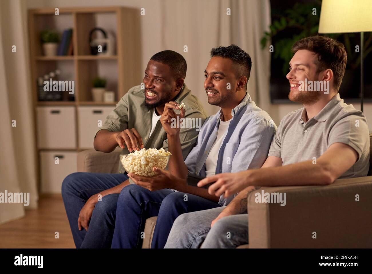 Männliche Freunde mit Popcorn, die zu Hause Fernsehen Stockfoto