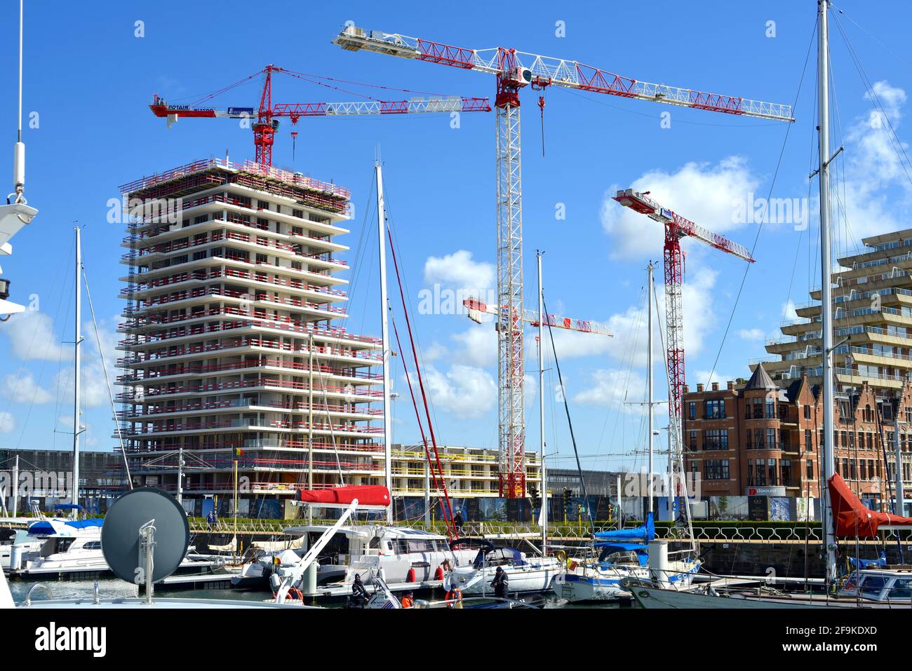 Ostend, Westflandern, Belgien - 17. April 2021: Wohnungsbau im Bau. Vor dem Schiff dockten Segelschiffe in Mercator Marina Oostende an. Stockfoto