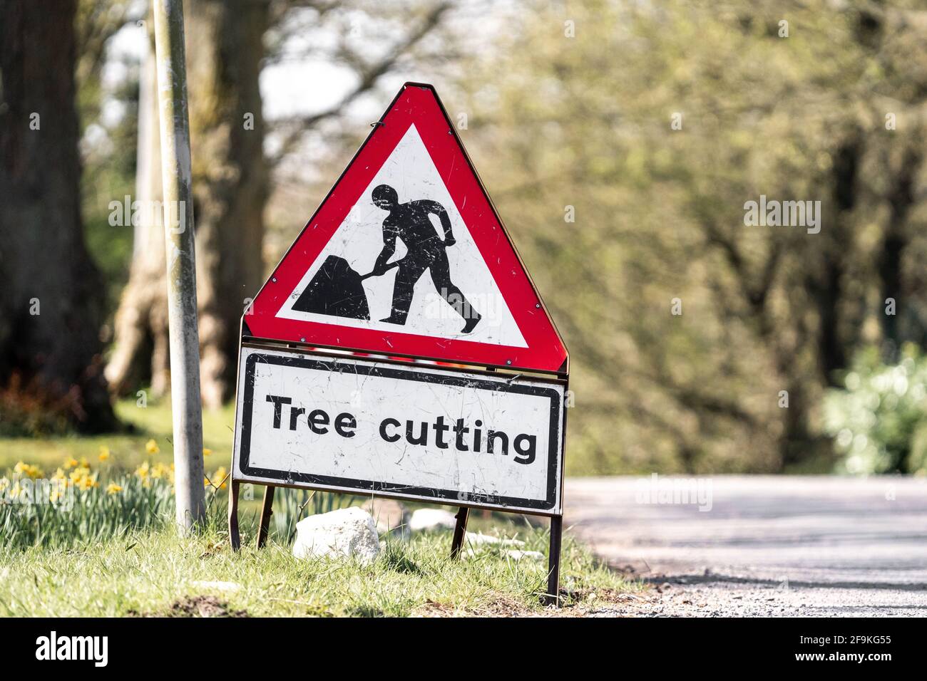 Rot-weißes Warnschild für den Baumschnitt, das am Straßenrand steht, mit dem Symbol für Straßenarbeiter. Verkehrsschild warnt Fahrer vor Gefahren. Stockfoto