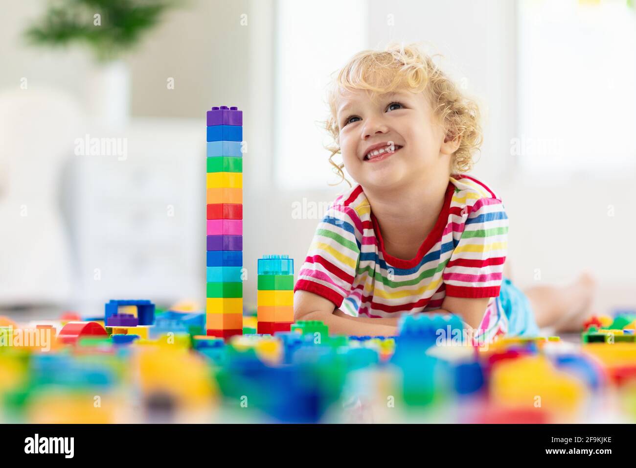 Kind spielt mit bunten Spielzeugblöcken. Kleiner Junge, der zu Hause oder in der Kindertagesstätte einen Turm baut. Pädagogisches Spielzeug für kleine Kinder. Stockfoto