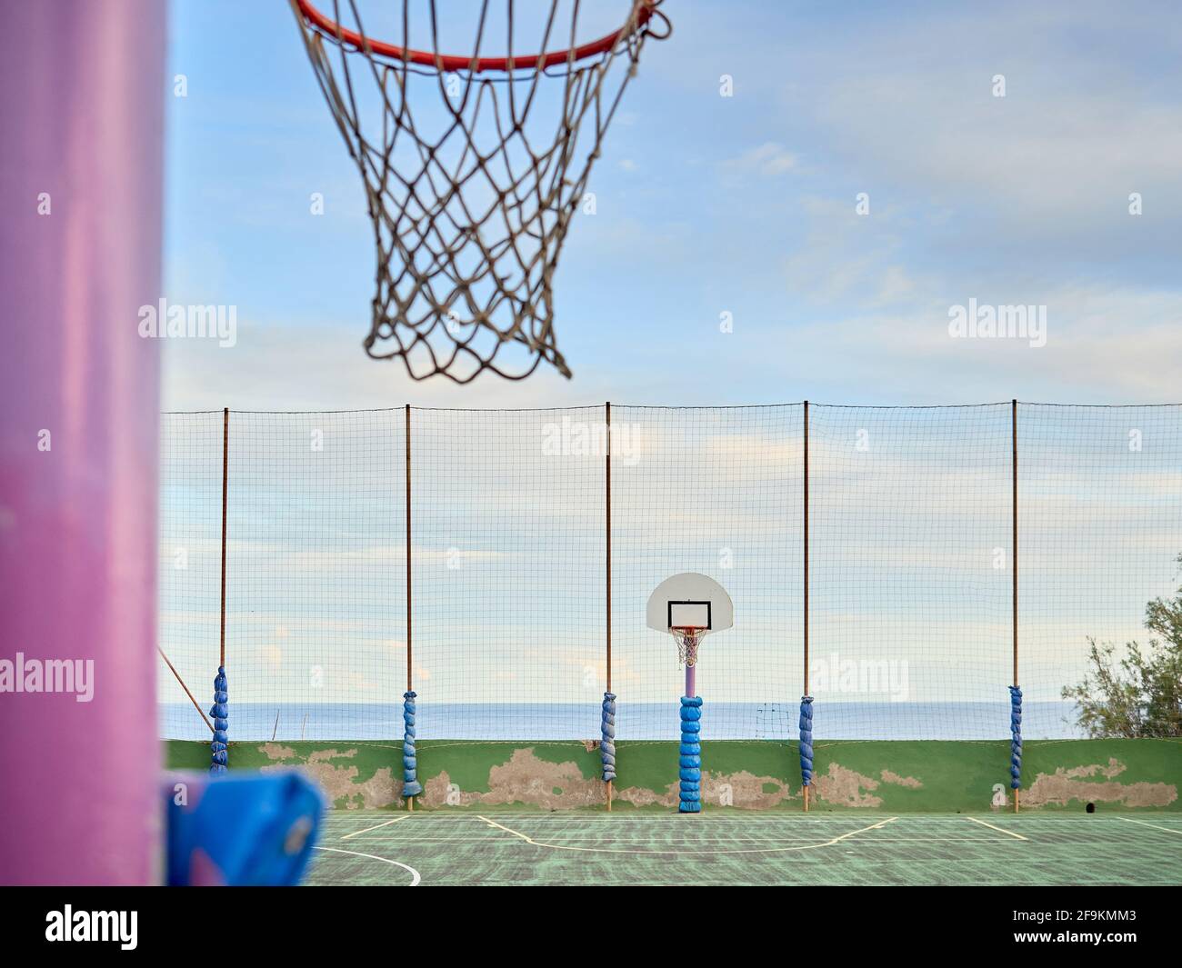 Vintage Basketballplatz ohne Menschen, neben dem Meer mit einem blauen Himmel mit Wolken Stockfoto
