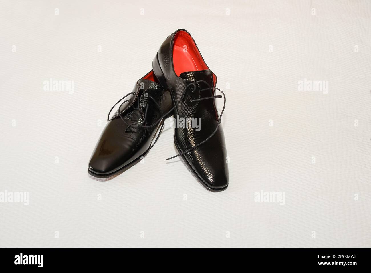 Ein Paar schwarze Herrenschuhe auf weißer Textiloberfläche. Stockfoto