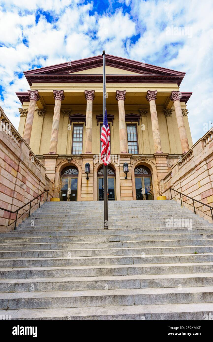 Lancaster, PA, USA - 18. April 2021: Die USA-Flagge fliegt am Halbmast am Eingang des älteren Teils des Lancaster County Courthouse in Lancaster Stockfoto