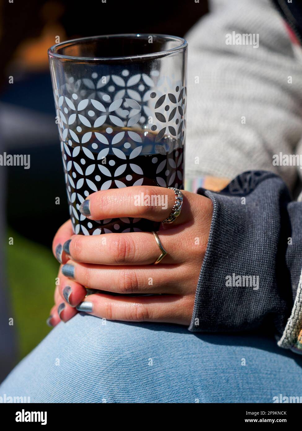 Hände einer jungen erwachsenen Frau mit einem Glas Cola, Großbritannien Stockfoto