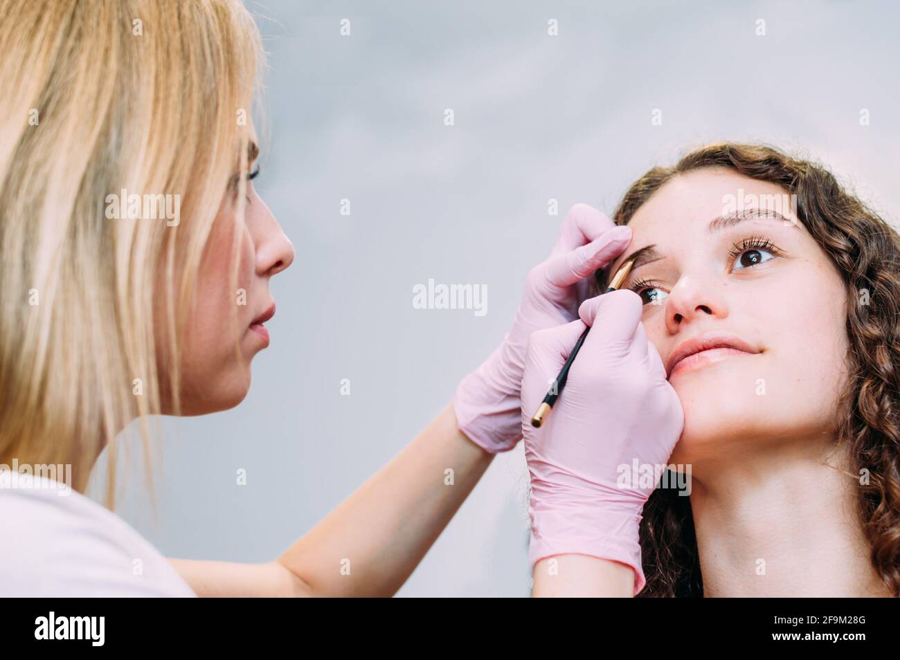 Augenbrauenmeister zeichnet die Form der Augenbrauen einer jungen Frau mit einem Augenbrauenstift. Henna Augenbraue Färbung Verfahren in einem Schönheitssalon Stockfoto