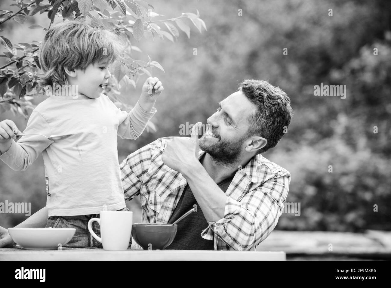 Familie Abendessen Zeit. Vater und Sohn essen im Freien. Glücklicher Vatertag. Kleiner Junge mit Vater essen Getreide. Sommer Picknick. Frühstück am Morgen. Gesundes Essen Stockfoto