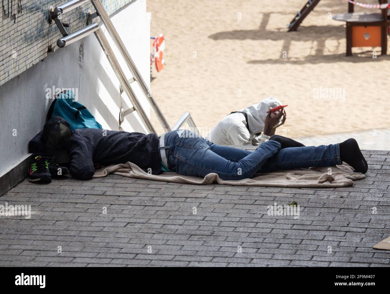 Las Palmas, Gran Canaria, Kanarische Inseln, Spanien. April 2021. Junge Migranten aus Afrika südlich der Sahara am Strand von Las Palmas auf Gran Canaria. Nach der gefährlichen Überfahrt von Afrika auf die Kanarischen Inseln haben viele die offiziellen Flüchtlingsunterkünfte aufgegeben und ziehen es vor, an den Stränden hart zu schlafen. Viele haben das Gefühl, dass sie abgeschoben werden, wenn sie in den Zentren bleiben. Im Jahr 2021 haben 34 Menschen bei der Überfahrt von Afrika auf die Kanarischen Inseln ihr Leben verloren. Quelle: Alan Dawson/Alamy Live News. Stockfoto