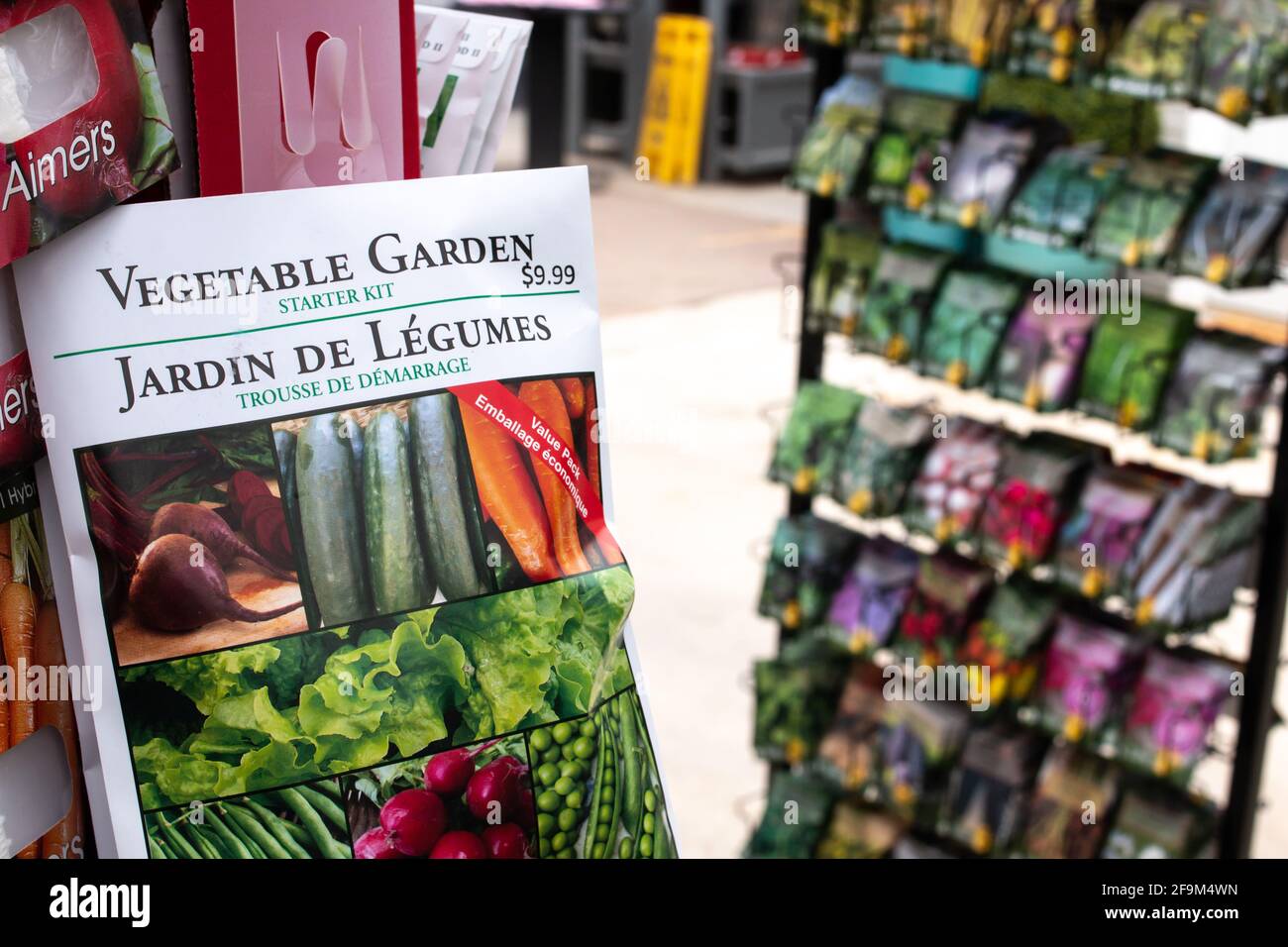 London, Ontario, Kanada - 7 2021. März: Eine weiße Packung Gemüsegarten-Samen, die an einem Haken hängen und andere Samensorten im Hintergrund verschwommen sind. Stockfoto