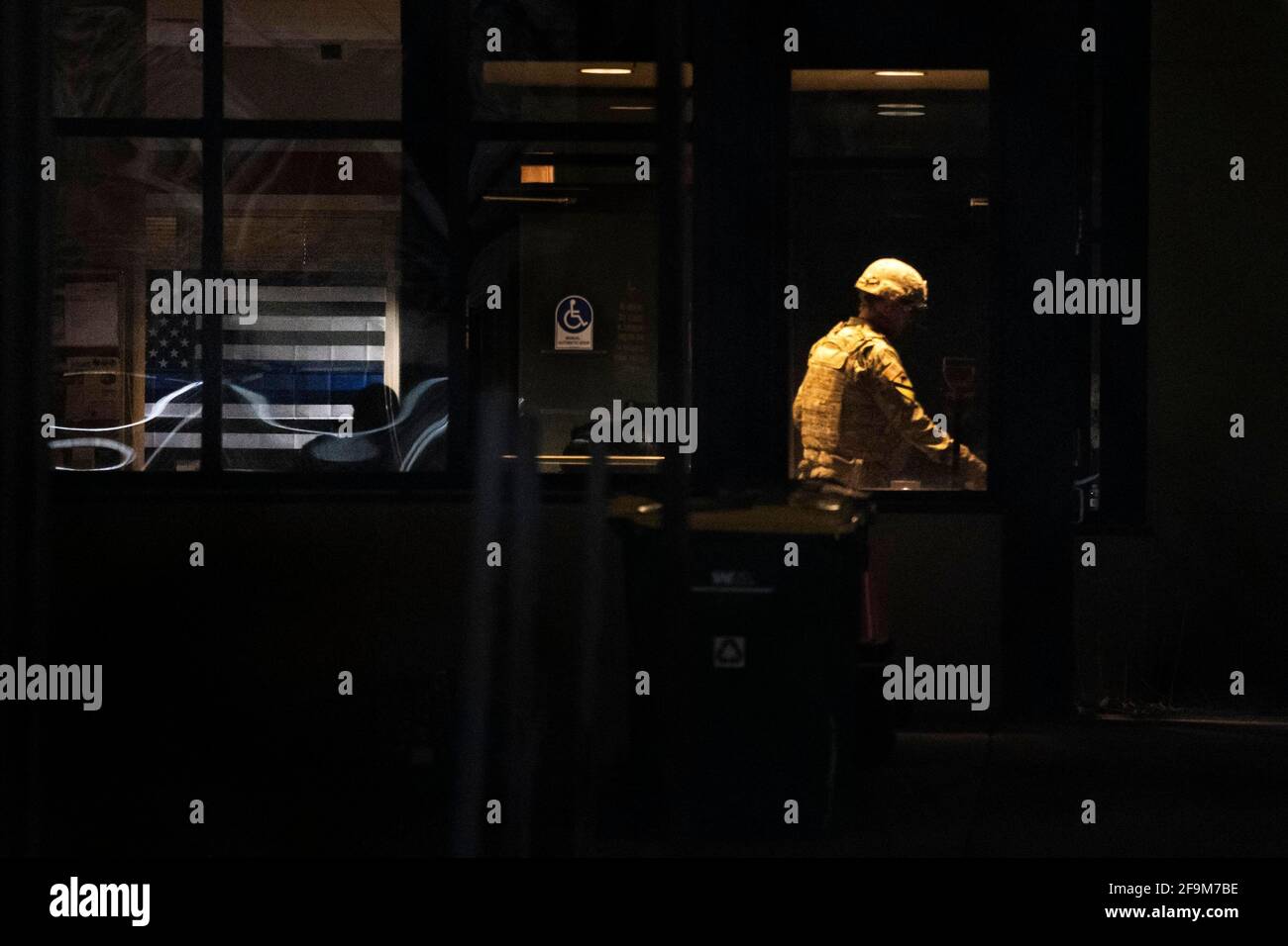 Brooklyn Center, USA. April 2021. Ein Mitglied der Nationalgarde verlässt am 17. April 2020 die Polizeiabteilung des Brooklyn Center, wo eine dünne blaue Linienflagge in der Lobby hängt. Die Proteste vor dem Polizeidezernat des Brooklyn Centers wurden in der siebten Nacht fortgesetzt, nachdem der ehemalige Beamte Kim Porter den 20-jährigen Daunte Wright bei einer Verkehrsbehinderungen getötet hatte. (Foto von Dominick Sokotoff/Sipa USA) Quelle: SIPA USA/Alamy Live News Stockfoto