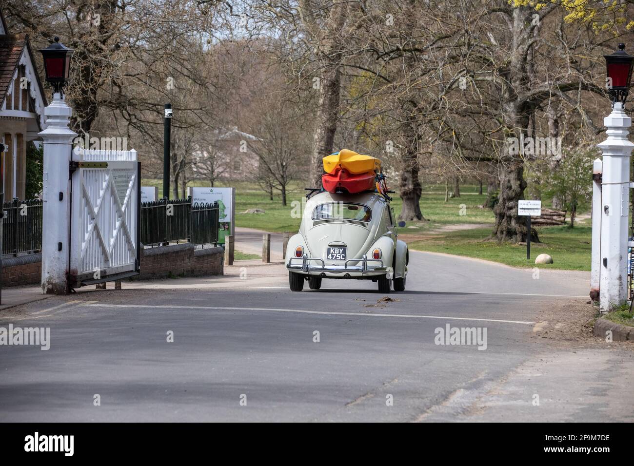 Ein Volkswagen Käfer mit Kanus auf dem Dach fährt durch den Eingang des Bishops Gate in Windsor Great Park, Surrey, England, Großbritannien Stockfoto