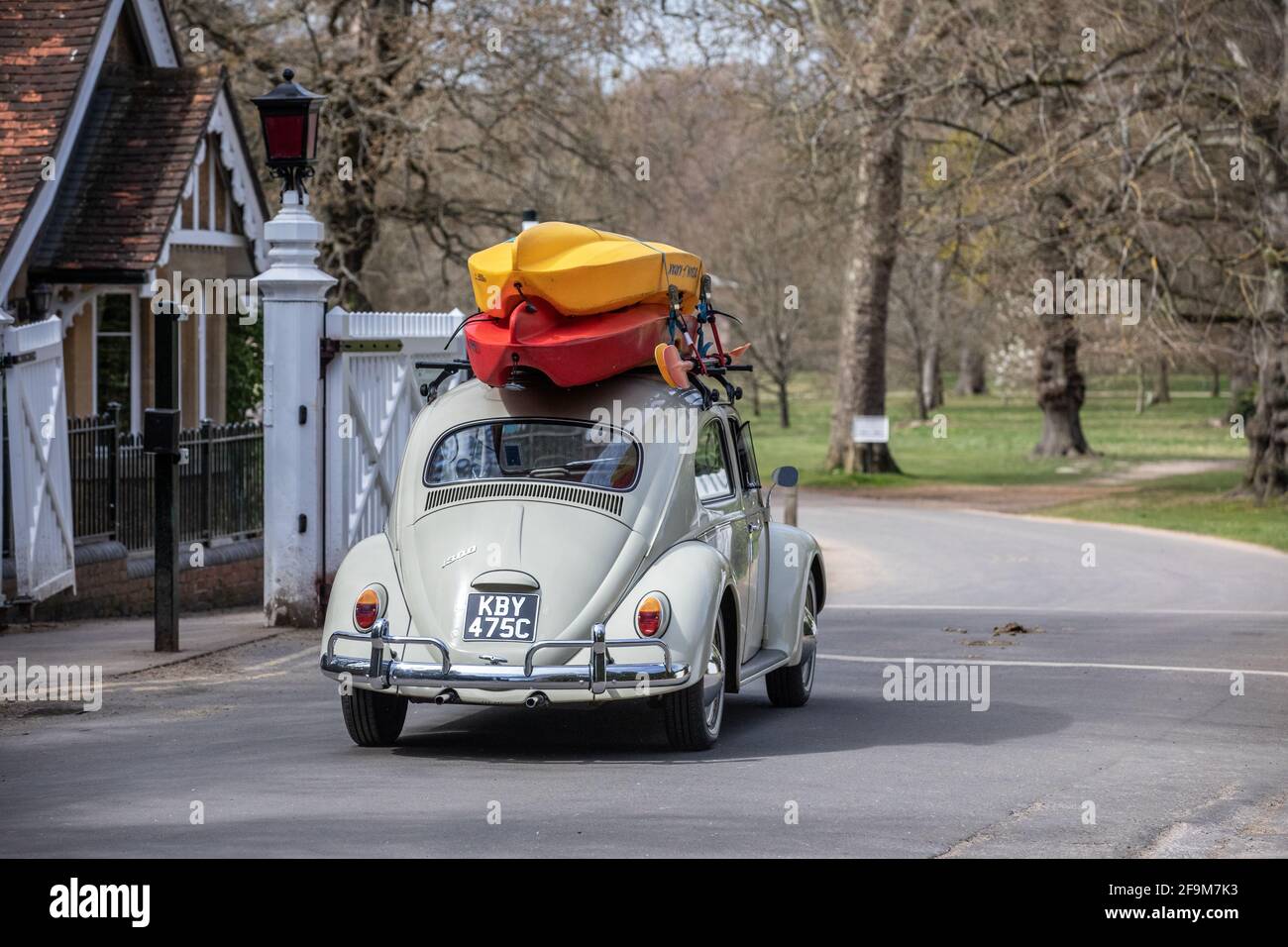 Ein Volkswagen Käfer mit Kanus auf dem Dach fährt durch den Eingang des Bishops Gate in Windsor Great Park, Surrey, England, Großbritannien Stockfoto
