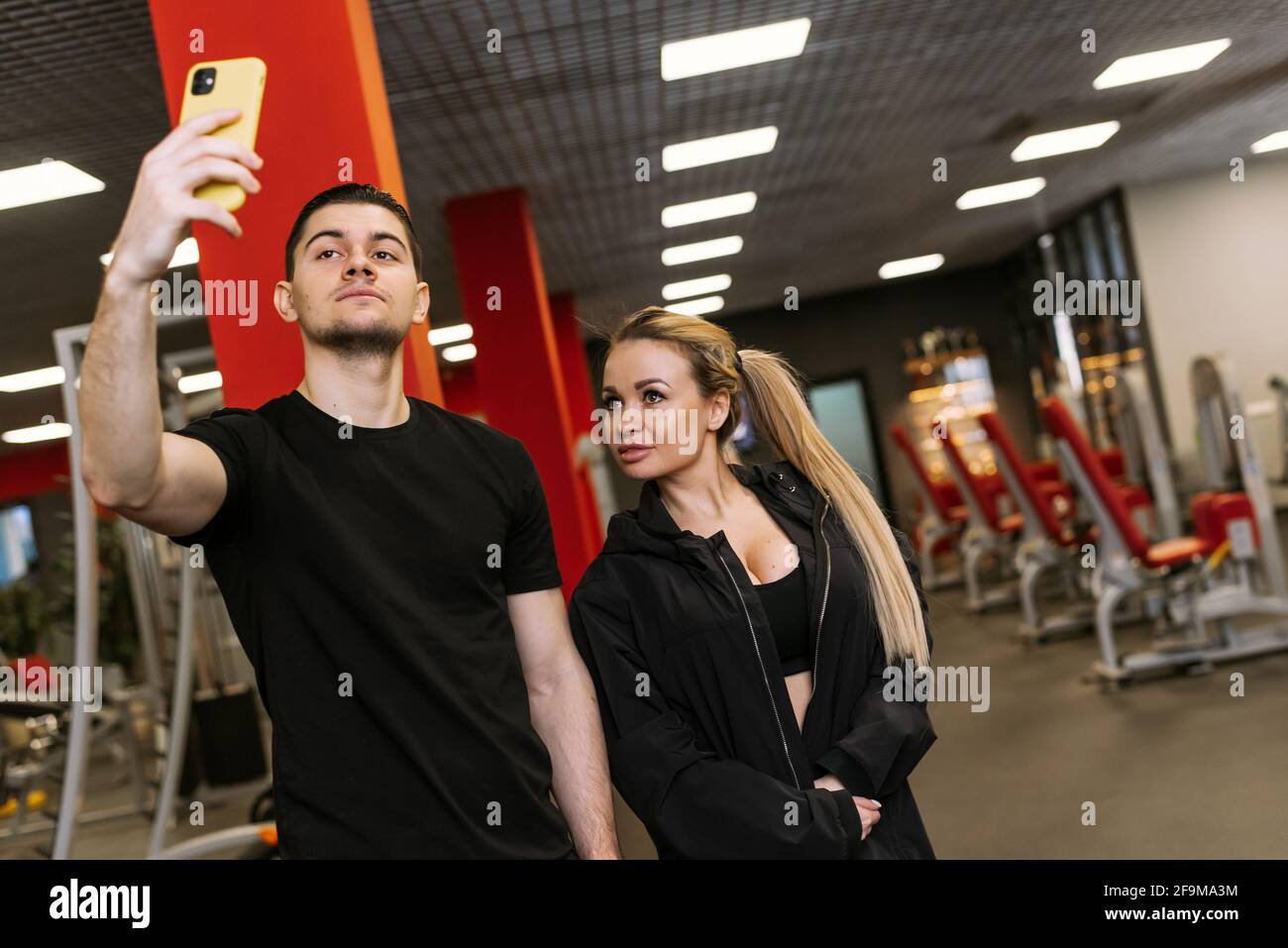 Persönliche Schulungen mit einem Trainer. Fitnesstrainer und Frau machen ein Selfie im Fitnessstudio. Stockfoto