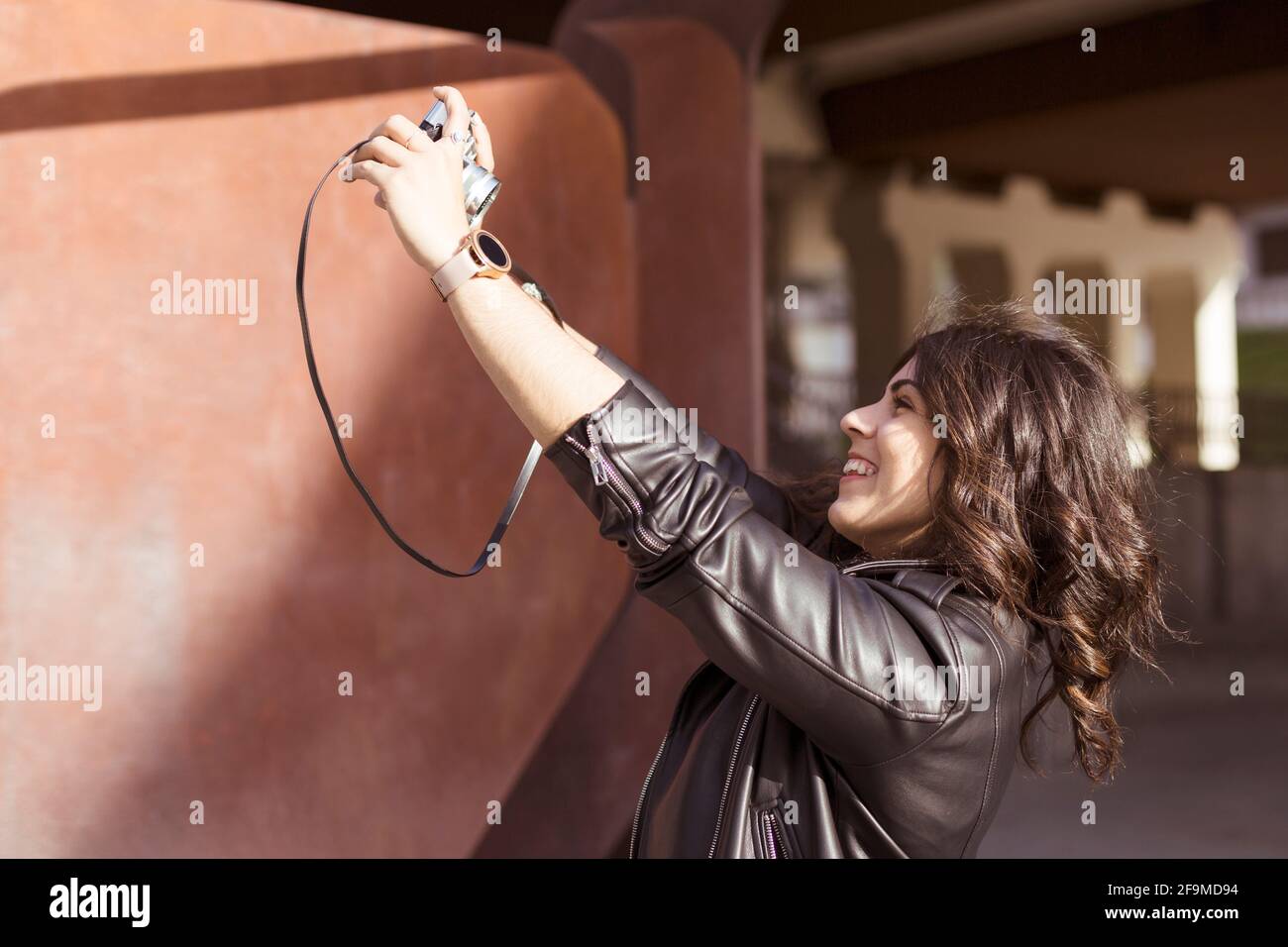 Junge glückliche kaukasische Frau, die mit einer analogen Kamera ein Foto von sich selbst macht. Platz für Text. Stockfoto