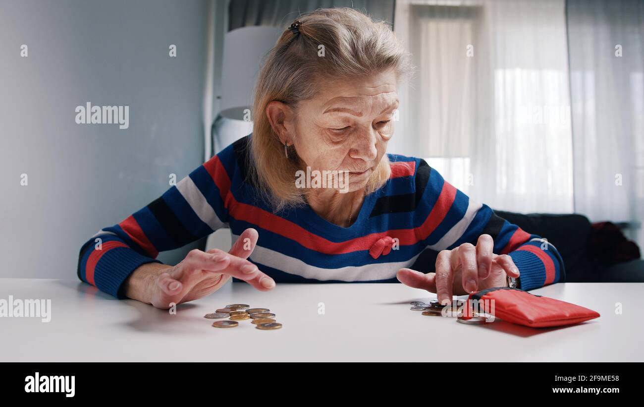 Arme alte Frau, die Münzen auf dem Tisch zählt. Niedrige Renten und unzureichende Mittel. Hochwertige Fotos Stockfoto