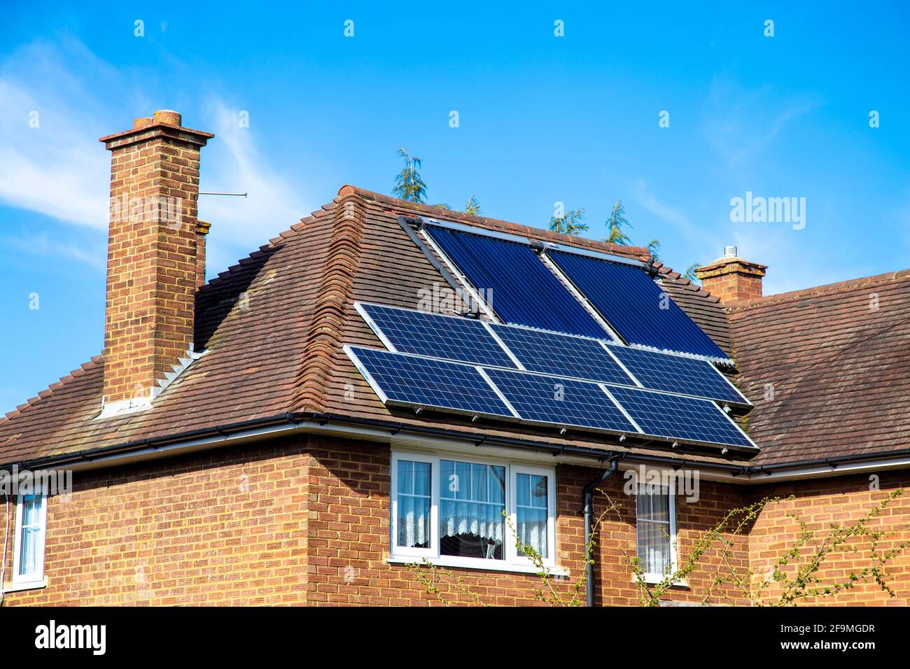 Ziegelhaus mit Solarzellen und Solarwasserheizpaneelen auf dem Dach in Hertfordshire, Großbritannien Stockfoto