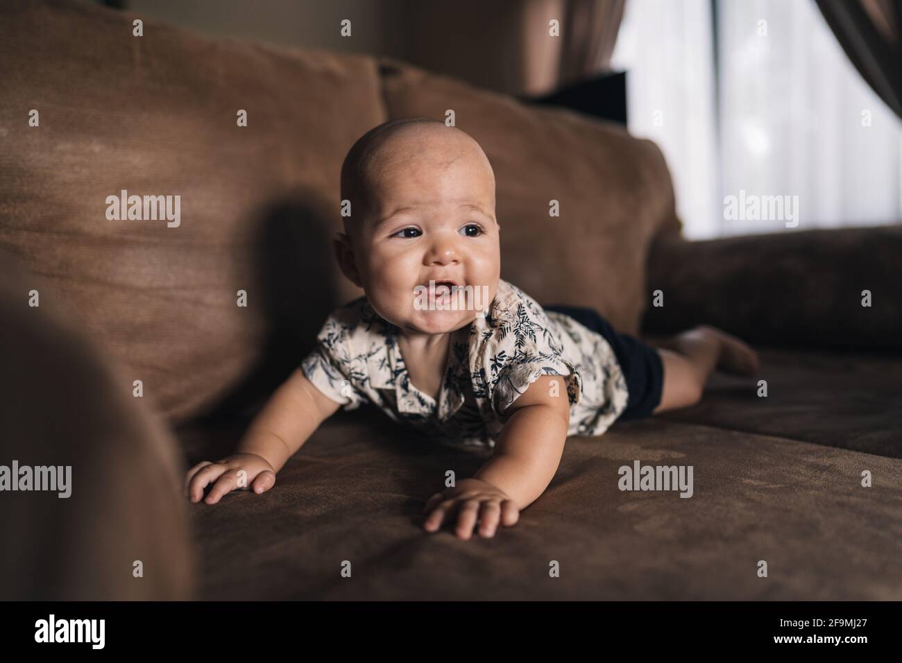 Cute Baby spielt auf der Couch lächelnd Stockfoto