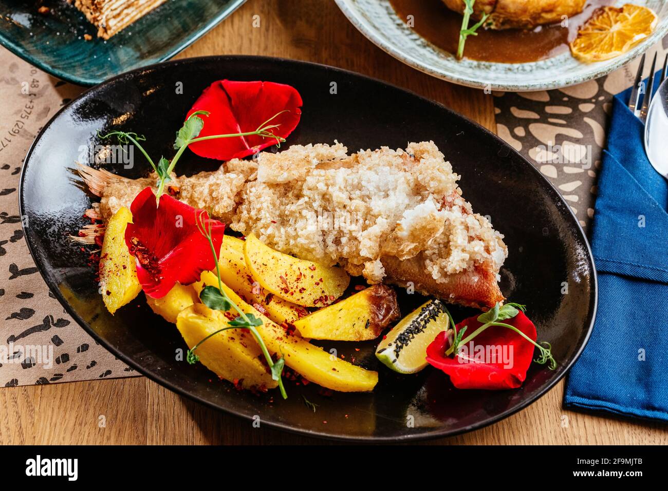 Gegrillter Fisch auf einem Teller mit Gemüse und Sauce Stockfoto