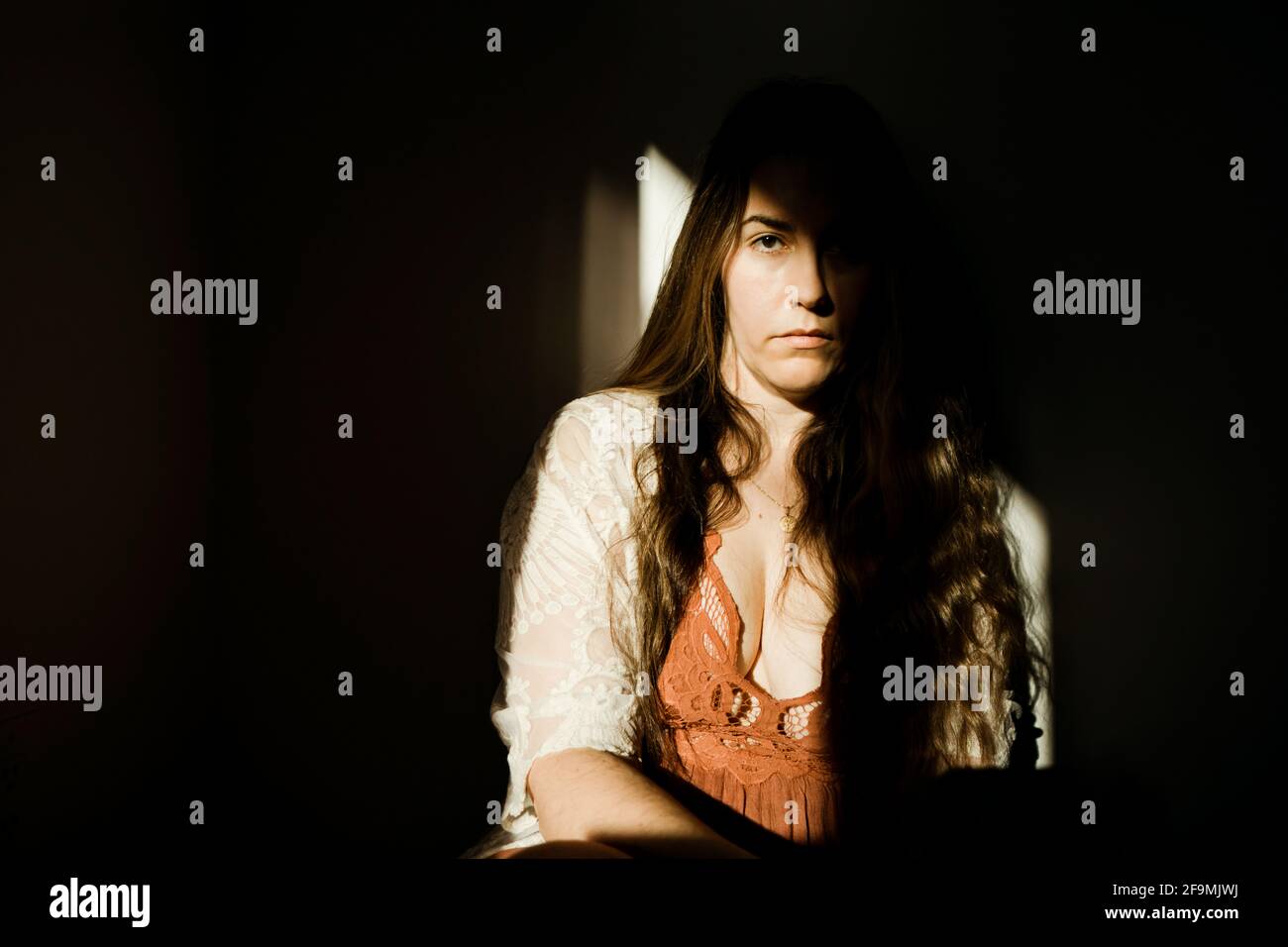 Eine Frau, die im Schatten sitzt und ein rotes Kleid trägt Stockfoto