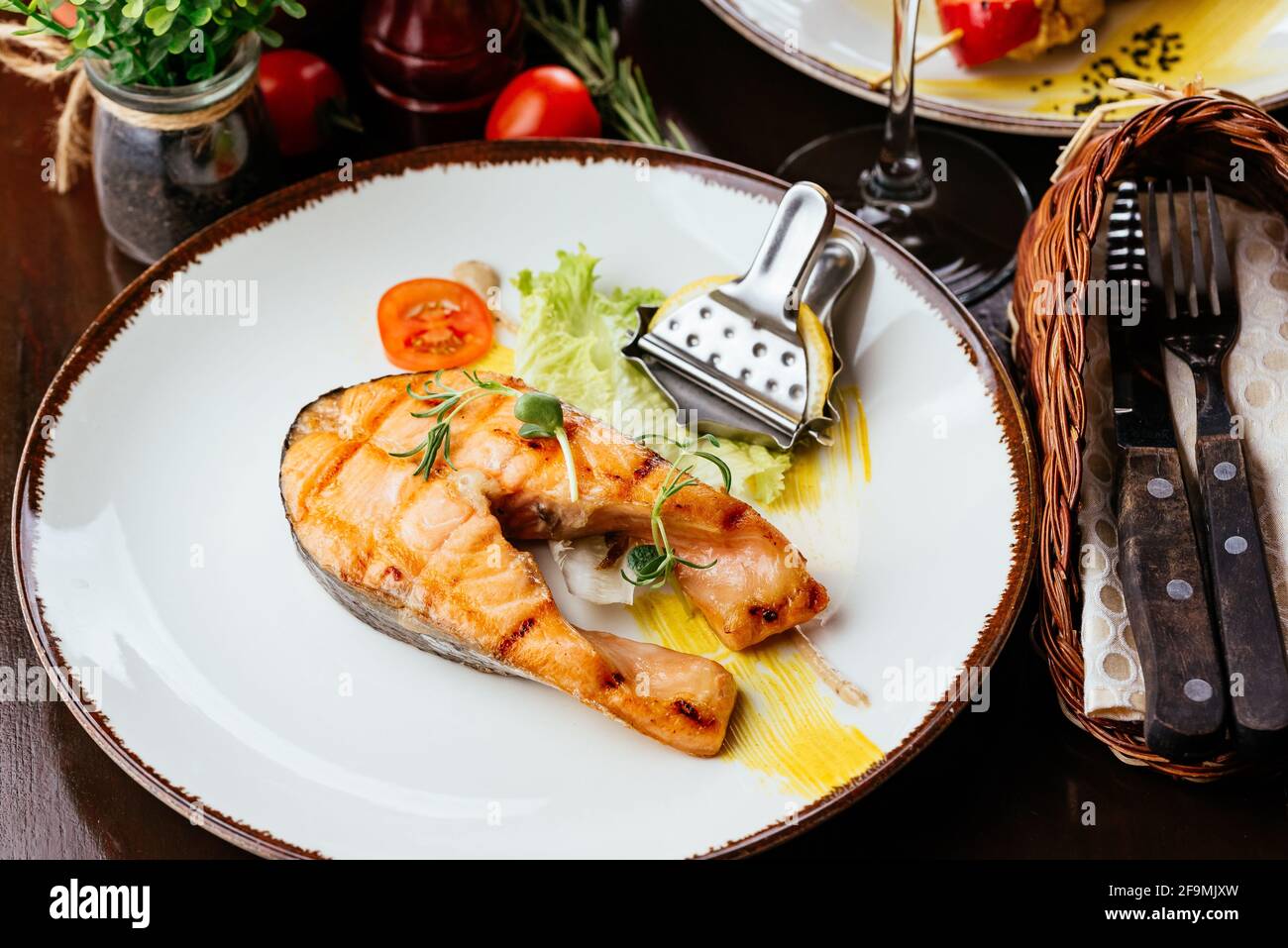 Gegrillter Fisch auf einem Teller mit Gemüse und Sauce Stockfoto