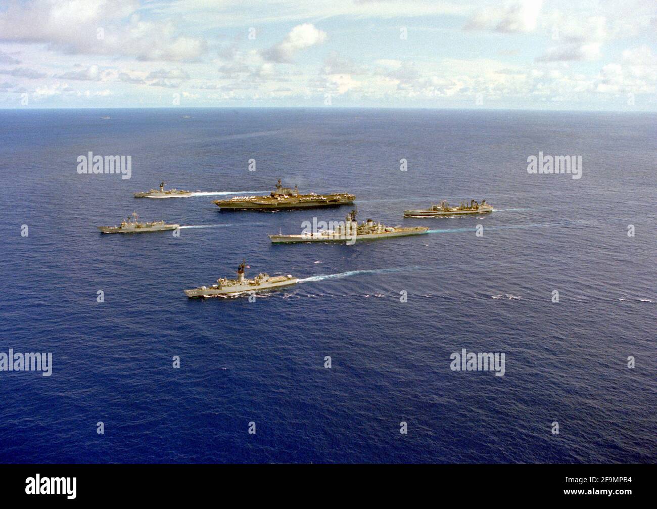 Eine Hafenansicht von Schiffen des Flugzeugträgers USS MIDWAY (CV-41), die in Formation unterwegs sind. Zu den Schiffen gehören von links die Fregatte USS MEYERKOD (FF-1058) und die Fregatte USS JOHN A. MOORE (FFG-19), vordere Reihe; das Schlachtschiff USS NEW JERSEY (BB-62), der Flugzeugträger USS MIDWAY (CV-41) und die Fregatte USS FRANCIS HAMMOND (FF-1067), Mitte und der Flottenöler UST-MISPILAO-105 hinten Stockfoto