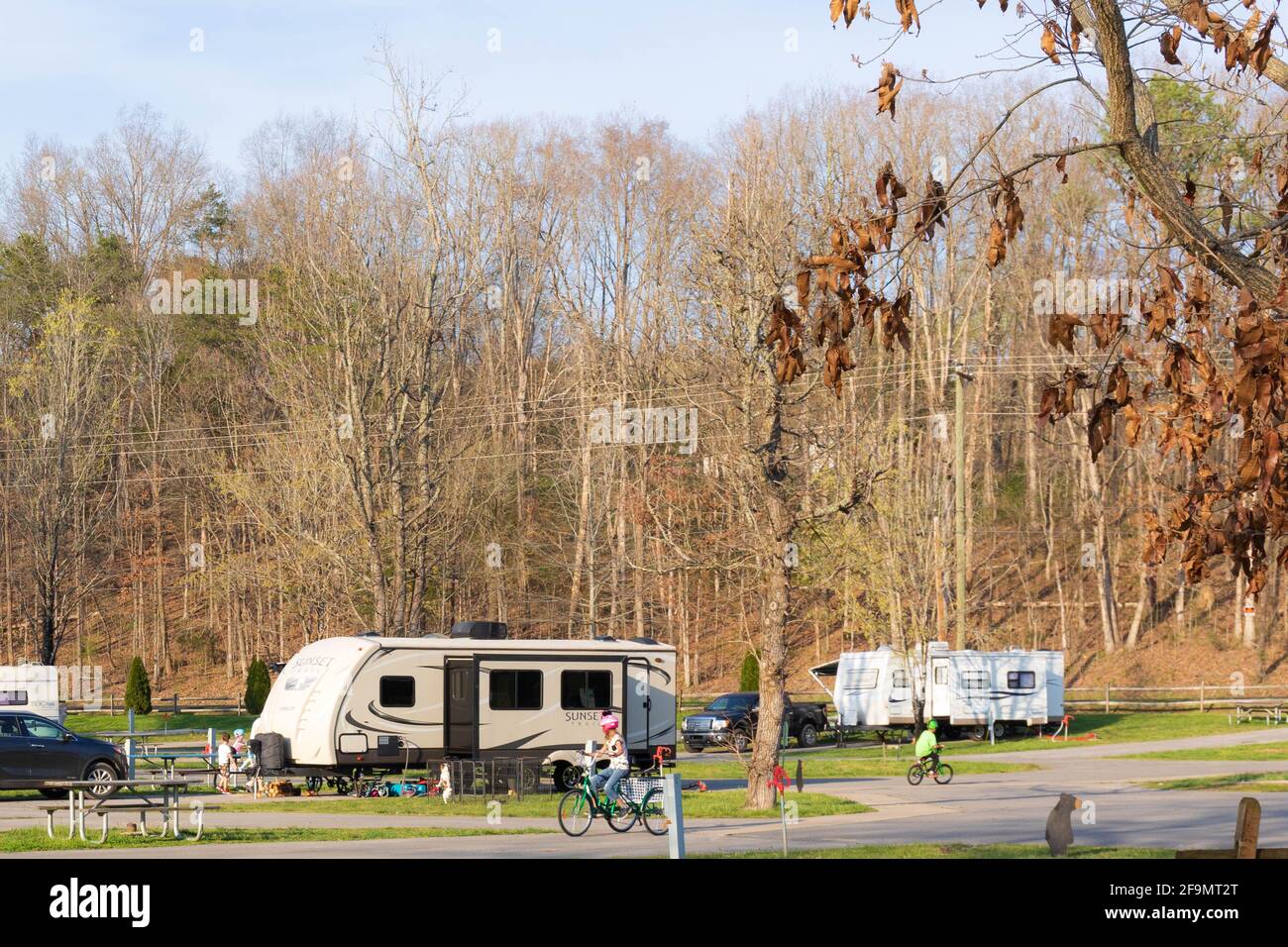 LIMESTONE, TN, USA--8 APRIL 2021: Ein Wohnmobil-Campingplatz mit Wohnwagen und Kindern, die spielen und Fahrrad fahren. Frühmorgens. Stockfoto