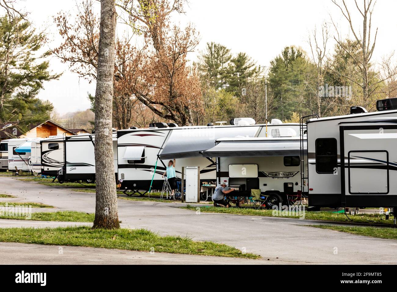 LIMESTONE, TN, USA--8 APRIL 2021: Ein vielbeschäftigter Wohnmobil-Campingplatz mit einer Reihe von Campingwagen und zwei Personen, die an ihren Wohnmobilen arbeiten. Frühmorgens. Stockfoto