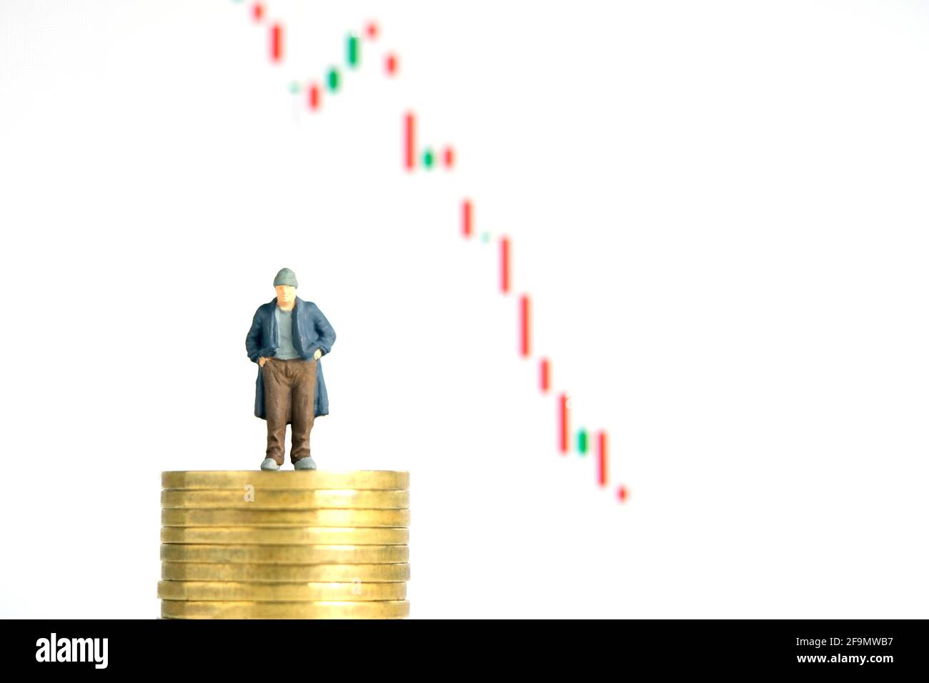 Miniatur kleine Menschen Spielzeug Fotografie. Die Menschen, die über dem Münzstapel stehen, haben kein Geld oder sind bankrott, die Aktienmarkt-Candle-Chart fiel herunter, isolieren Stockfoto