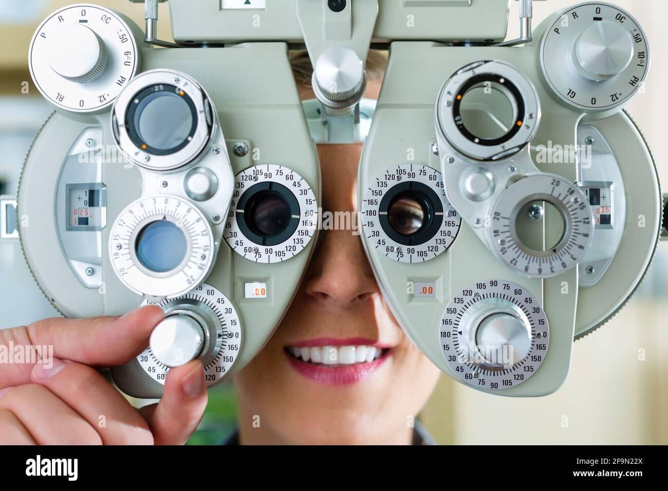 Junge Frau am Phoropter beim Optiker oder Augenarzt für Sehtest, ist sie kurzsichtig oder weitsichtig Stockfoto