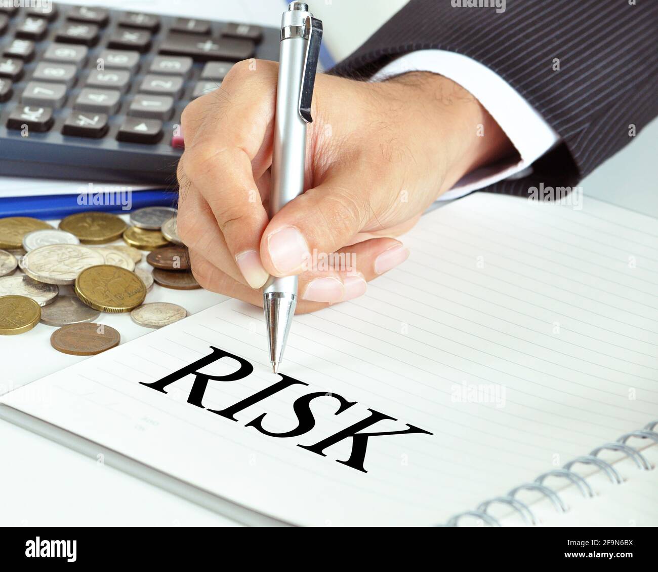 Hand mit Stift, der auf DAS RISIKO-Wort auf dem Papier zeigt - Finanz- und Geschäftskonzept Stockfoto